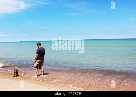 Hund und Besitzer auf dem Michigansee Stockfoto