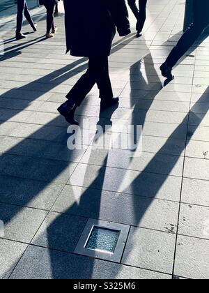 Pendler mit langen Schatten auf dem Bürgersteig im Januar Stockfoto