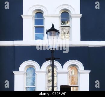 Eine Straßenleuchte vor einem Haus in der Londoner Portobello Road Notting Hill entspricht dem Architekturstil, wie er durch die Fenster und die bemalte Fassade im Hintergrund dargestellt wird Stockfoto