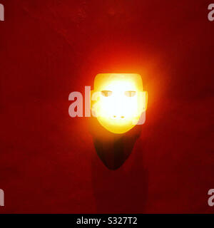 Eine von einer elektrischen Glühlampe beleuchtete Steinmaske wird im Templo Mayor Museum in Mexiko-Stadt ausgestellt Stockfoto