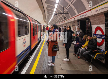 Eine Dame wartet darauf, an einem Zug der Londoner U-Bahn anzusteigen, der gerade am Bahnhof angekommen ist Stockfoto