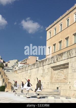 Wachwechsel (Evzones) am Grab des Unbekannten Soldaten in Athen, Griechenland, vor dem griechischen Parlament. Das Grab im Art Deco-Stil zeigt einen toten männlichen Krieger, der mit Schild und Helm liegt. Stockfoto