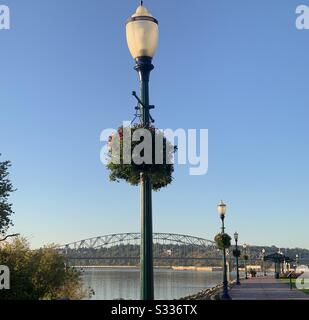 Dubuque, IOWA, Herbst 2019 - Landschaftsfoto der historischen schwarzen Metall-Lampenpfosten, die gepflasterten Flusslauf mit Brücke über Mississippi River im Hintergrund am sonnigen Herbsttag sägen. Stockfoto