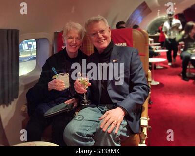 Erstklassiges erfolgreiches Paar mit Cocktails im Connie, einer Cocktailbar im Inneren eines Sternenflugzeugs der 1950er Jahre im TWA-Hotel am JFK Airport, NYC, USA Stockfoto