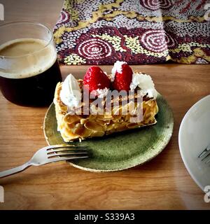 Ein Stück napoleon Pastete mit Erdbeeren und Mille-feuille auf einem grünen Teller mit einer Tasse Kaffee Stockfoto