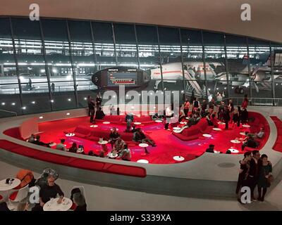 Die versunkene Lounge im TWA Hotel ist das Zentrum der restaurierten Lobby, wie nachts mit der Connie Airplane Cocktailbar auf dem Asphalt draußen, JFK, NYC, USA, zu sehen ist Stockfoto