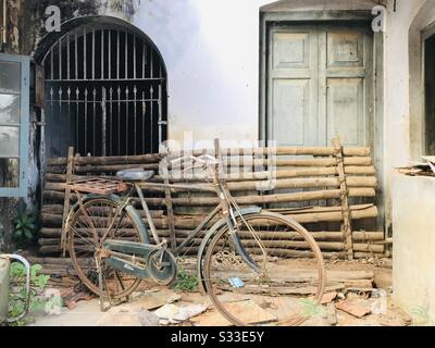 Ein altes Gebäude, das für das Haufen von Dingen benutzt wird, ein altes Fahrrad, Bambusstangen alter Metallstuhl, kaputte Tonfliesen mit gegrilltem Fenster und Holztür, ein klassischer Vintage-Look - rustikale Gegenstände Stockfoto