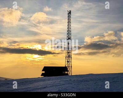 Silhouette von Haus und Sendeturm bei Sonnenuntergang im Winter Stockfoto