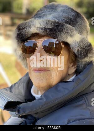 Porträt einer neunzigjährigen Frau mit Sonnenbrille während eines Wintertags Stockfoto