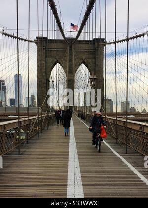 Menschen, die auf der legendären Brooklyn Bridge in New York City spazieren gehen und radeln Stockfoto