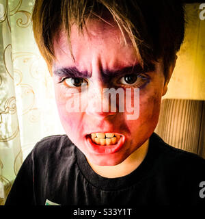 Ein zehnjähriger Junge mit Film-Make-up auf Snarls an der Kamera. Stockfoto