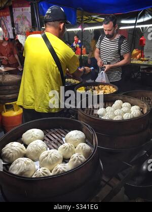 Ein Mann verkauft Cha siu bao (gedämpfte BBQ Schweinebüsen) und andere verschiedene Dim Sum Knödel auf einem Nachtmarkt, Kuala Lumpur, Malaysia Stockfoto