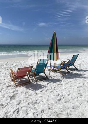 Farbenfrohe Sonnenliegen und Sonnenschirm am weißen Strand mit Blick auf das smaragdgrüne Wasser des Golfs von Mexiko Stockfoto