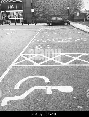 Behinderten-Parkplätze auf einem Parkplatz, außerhalb von Geschäften in England, Großbritannien Stockfoto