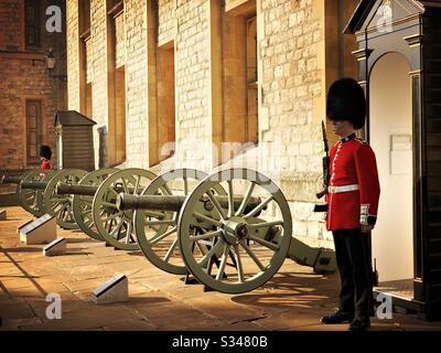 Die Schotten Gurad Sentry und königliche Waffenkanonen stehen außerhalb des Jewel House. Lage der Kronjuwelen. Waterloo Block, Tower of London. UNESCO-Weltkulturerbe. Stockfoto