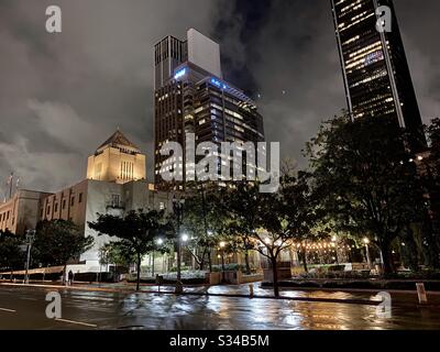 LOS ANGELES, CA, MAR 2020: LA Public Library, Central Branch in Downtown mit nahe gelegenen Wolkenkratzern dahinter. Nasse Straßen von Regen reflektieren nachts die Beleuchtung der Stadt Stockfoto