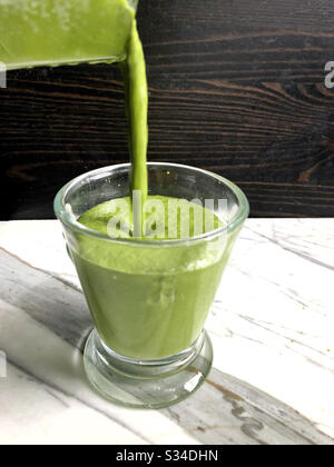 Grüner Smoothie in einem Mixer zu Hause mit Avocado, grüner Banane, Ingwer, Kokosöl und Spinat. Stockfoto