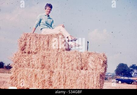 Alte schöne Frau, die auf einem riesigen Heuhaufen sitzt Stockfoto