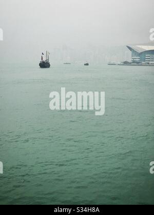 Das "Aqua Luna", ein nachgebildeter chinesischer Schrott, der für Touristenbesichtigungen verwendet wird, am Victoria Harbour an einem verschneiten Tag in Hongkong Stockfoto