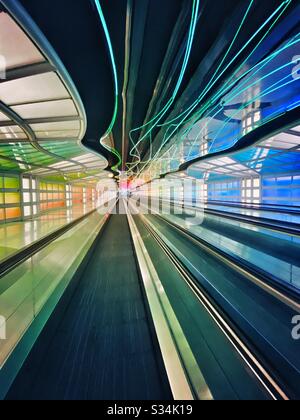 O'Hare International Airport. Tunnel zwischen den Konkursen B und C des United Terminal mit beweglichen bunten Neonleuchten und bewegtem Gehweg. Stockfoto