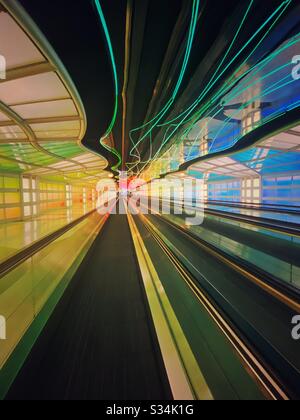 O'Hare International Airport in Chicago, Illinois. Tunnel zwischen den Konkursen B und C des United Terminal mit beweglichen bunten Neonleuchten und bewegtem Gehweg. Stockfoto