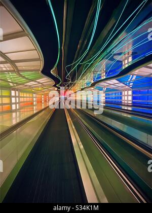 O'Hare International Airport in Chicago, Illinois. Tunnel zwischen den Konkursen B und C des United Terminal mit beweglichen bunten Neonleuchten und bewegtem Gehweg. Stockfoto