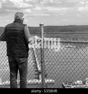 DUBUQUE, IOWA, 12. April 2020 - Schwarz-Weiß-Foto von älteren männlichen Blick über Lock and Dam #11 aus Eagle Point Park an sonnigen Tag. Stockfoto