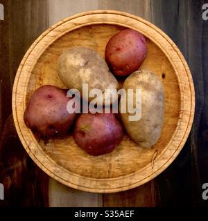 Stillleben von 3 roten Kartoffeln und 2 weißen Kartoffeln in einer Holzschüssel. Stockfoto