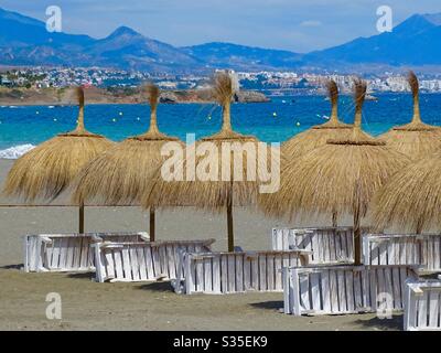 Liegestühle und Sonnenschirme an einem leeren Strand in Südspanien während der Sperrung des Coronavirus Stockfoto