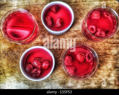 Veganes Himbeer-Gelee mit Himbeeren in Ramekin-Gerichten auf einem Holzhackbrett Stockfoto