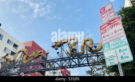 LOS ANGELES, CA, APR 2020: Blick auf Twin Dragon Gateway, geschnitzte Golddrachen und Parkschilder am Rande von China Town in Downtown LA Stockfoto