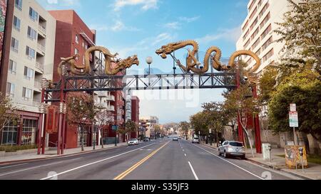 LOS ANGELES, CA, APR 2020: Blick auf die Straße des Twin Dragon Gateway, geformt Golddrachen, am N Broadway, am Rande von China Town in Downtown LA. Neue Wohnungen und leichter Verkehr Stockfoto