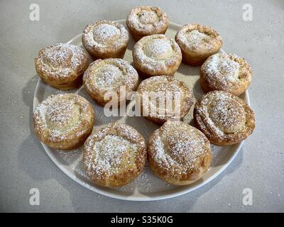 Hausgemachte Mince Pies. 12 Pasteten auf einem Teller mit Puderzucker bestreuen. Stockfoto