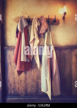 Alte Kleider hängen an Kleiderbügeln. Wand aus Holz. Ein Licht scheint Stockfoto