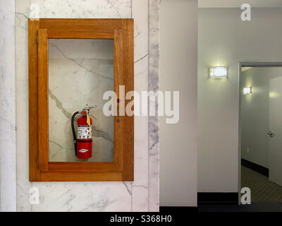 LOS ANGELES, CA, APR 2020: Feuerlöscher in Glasschrank auf Marmorwand, in einem Downtown-Apartmentgebäude Stockfoto