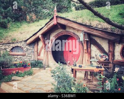 Hobbiton. Bukolischer Ort in Neuseeland, wo die Hobbits aus der Mittelerde leben. Lord of the rings Filmset. Rote runde Holztür Stockfoto