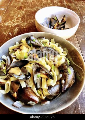 Muscheln in Knoblauchbutter mit Erbsen und Fettuccine. Stockfoto