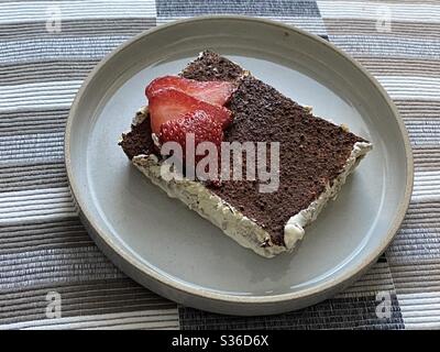 Tiramisu, italienisches Dessert mit Kaffeegeschmack, mit in Kaffee getauchten Schwammfingern, mit einer Mischung aus Eiern, Zucker und Mascarpone-Käse, mit Kakao gewürzt. Gekrönt mit Erdbeere in Scheiben Stockfoto