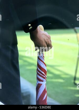 Mann in Anzug hält geschlossen rot und weiß Regenschirm Wimbledon London England Stockfoto
