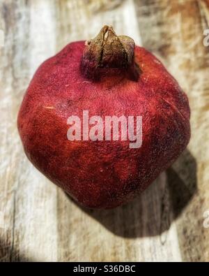 Granatapfelfrucht, dicke lederrote Haut mit essbaren pinksaftigen Samen Stockfoto