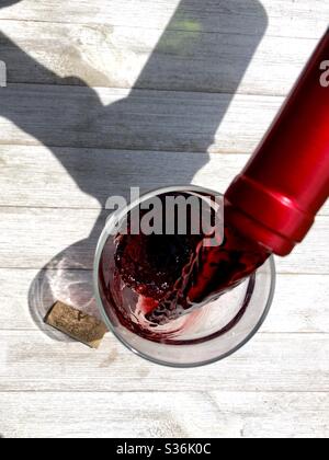 Rotwein wird in ein Glas gegossen Stockfoto