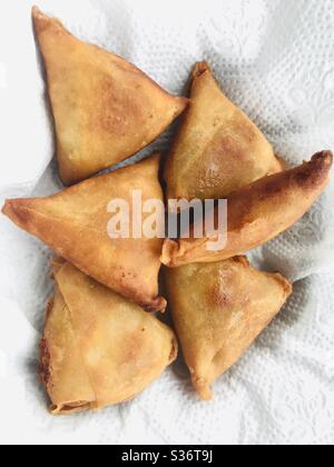 Hausgemachte dreieckige Form gebratenes Gemüse gefüllte Samosa, ein beliebter Snack in Indien & Südasien, in Küchentuch platziert, um überschüssiges Öl abzulassen Stockfoto