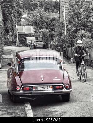Rückseite des Oldtimer Citroën DS Auto mit Frau, die vorbei radeln Stockfoto