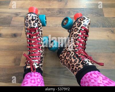 Beine und Füße der Frau tragen Rollschuhe mit Leopardendruck und Leggings mit pinkem Leopardendruck, die sich im POV-Look befinden Stockfoto