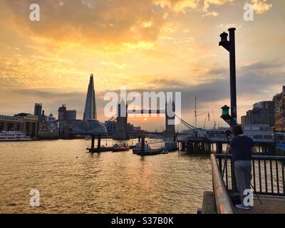 Ein Mann fotografiert einen Blick auf die Tower Bridge und den Shard Wolkenkratzer bei Sonnenuntergang auf der Themse Stockfoto