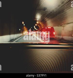 Autos fahren durch den Tyne Tunnel in Nordostengland. Durch die Windschutzscheibe sind unscharfe rote Bremsleuchten zu sehen. Verkehrsinfrastruktur. Stockfoto