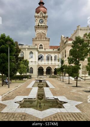 Zentraler Uhrturm mit kupferfarbener Zwiebelkuppel und Teich in Form des islamischen Symbolsterns Rub el Hizb im Sultan Abdul Samad Building Kuala Lumpur Malaysia Stockfoto