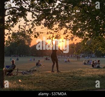 Frau auf Slack Line bei Sonnenuntergang in Clapham Common Stockfoto