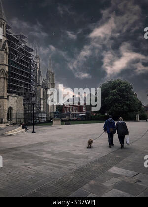 Ehepaar, das während der Covid 19-Sperre ihren Hund außerhalb des York Minster herumläuft Stockfoto