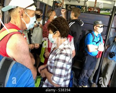 Passagiere im Bus des öffentlichen Nahverkehrs mit Gesichtsmasken während der Pandemie Covid 19, Saas Fee, Schweiz. Stockfoto